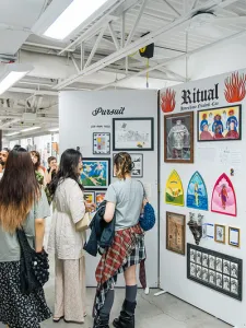 Group of people walking around GradEx 110, seeing illustrations on plinths