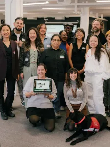 A group of individuals posing in front of the camera at an office setting.