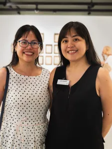 Two women side by side in an art gallery.