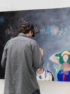 An artist doing final touches to a large abstract painting hanging on the wall