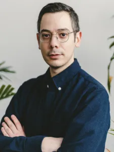 headshot of Erdem Tasdelen wearing a deep blue collar shirt with his arms crossed