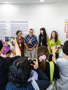 Four people standing at the back with people taking photos of them
