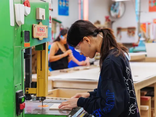 Student cutting wood on a band saw