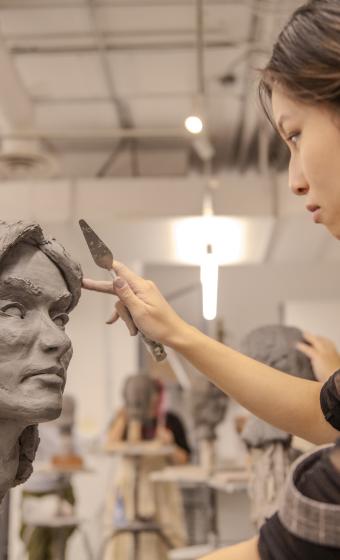 Person working on a clay sculpture.