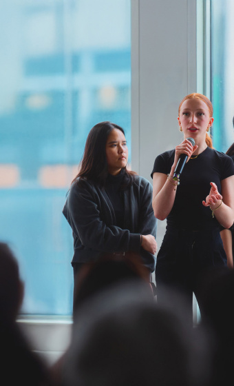 3 people speaking in front of a seated crowd