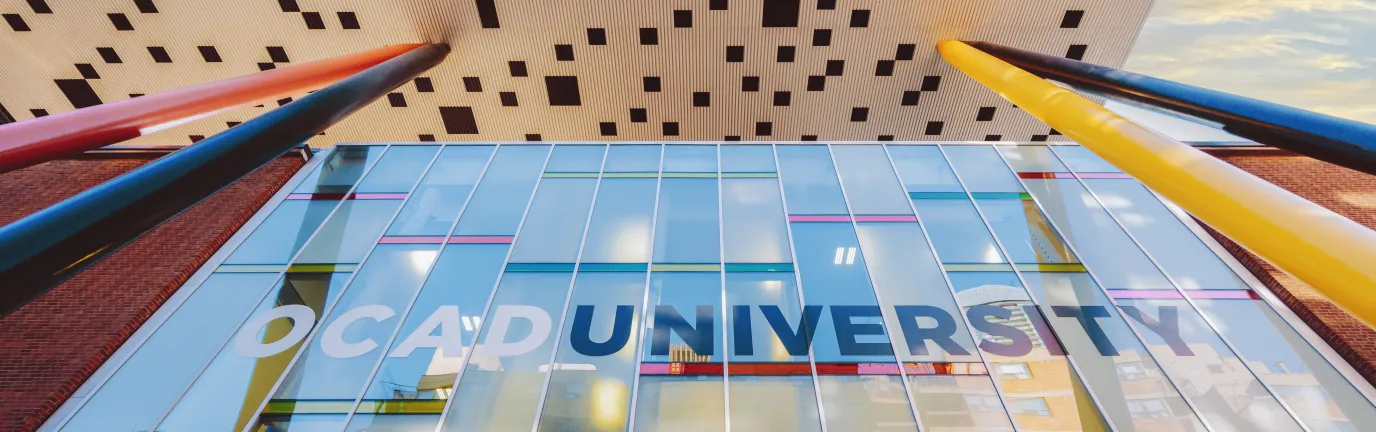 View from below of a white and black checkered building with a glass wall.