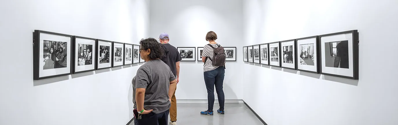 White gallery walls with hanging artwork, people browsing