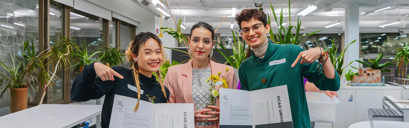 Three students holding their degrees