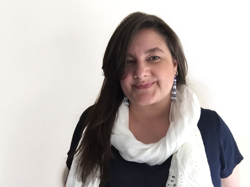 A woman with long black hair wearing black t-shirt and white scarf