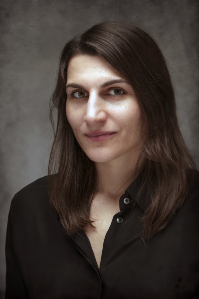 A woman with long black hair black shirt smiling at the camera