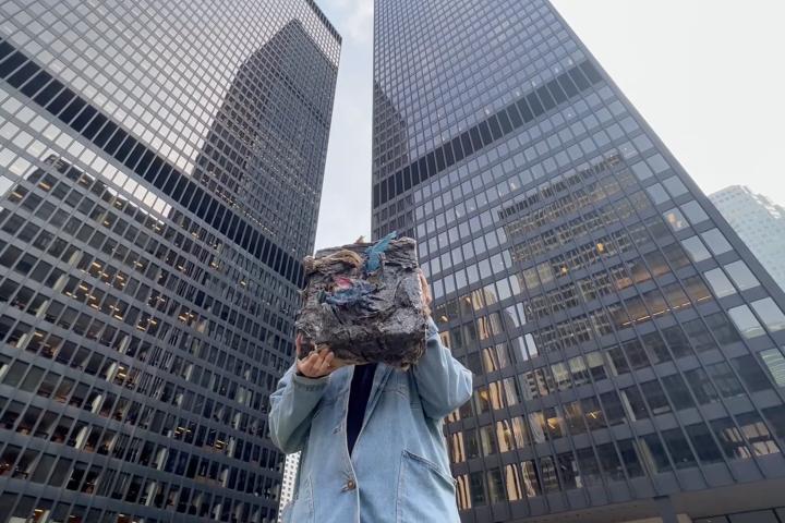 a person holding art standing between two buildings