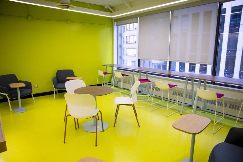 a room with bright yellow floors and walls, with white chairs around tables.