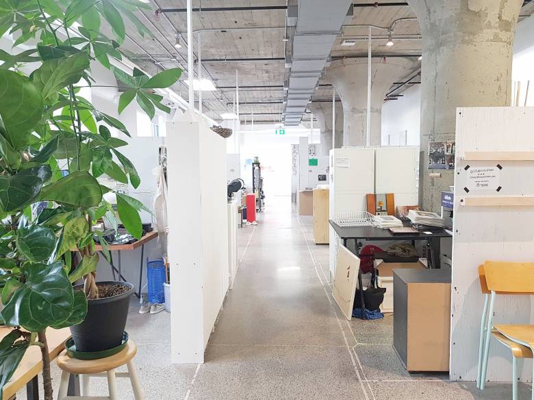 Photo of white studio hallway with plant on left and tables on right