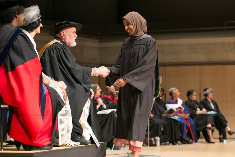Chancellor is handing a degree to a student who is crossing the date