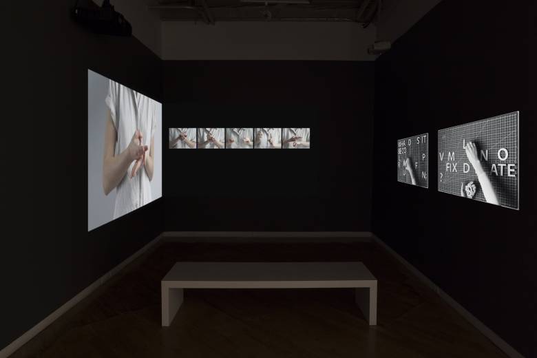 Image of projected video featuring hands and shapes in grey