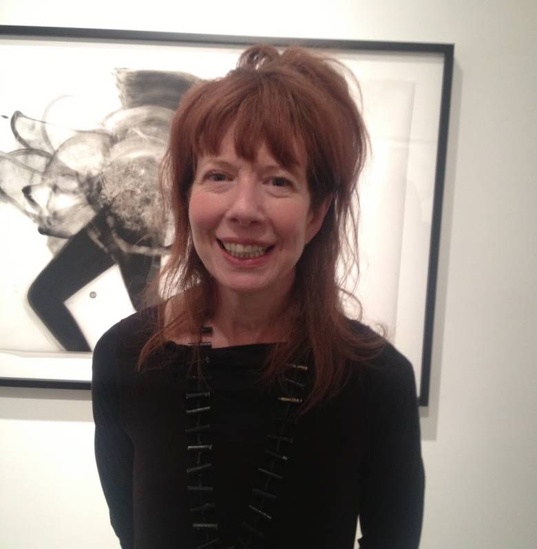 A photo of Cathy Daley standing in front of one of her drawings.