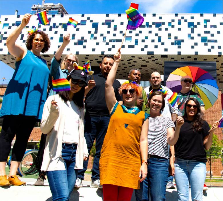 2019 photo of OCAD U staff waving Pride flags. Taken from Grange Park, adjacent to campus, the Rosalie Sharp Centre for Design can be seen in the background.