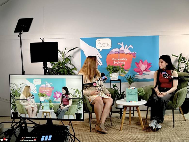 Two women, one at left and one at right, in a studio videotaping a TV program.