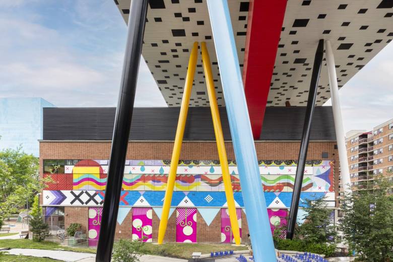 Jordan Bennett's multi-coloured mural on side of OCAD U building and multi-coloured steel legs below table-top design.