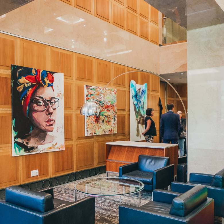 Corporate wooden wall with black leather chairs and paintings of portraits hung across
