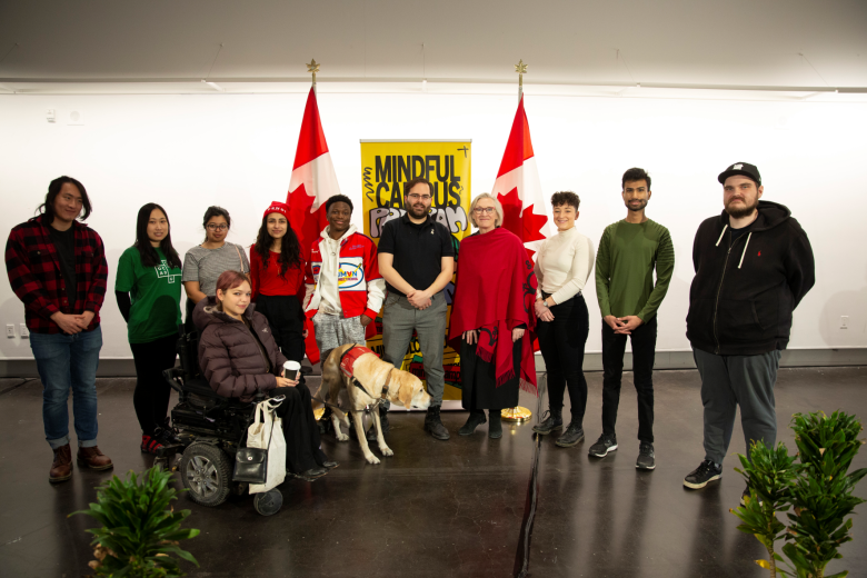 Minister Carolyn Bennett standing, wearing a red cape, with OCAD U students