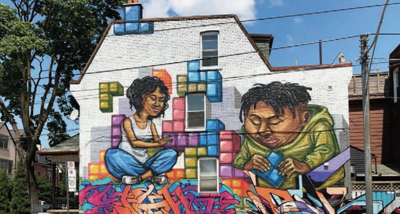 The side of a house in Toronto painted with a colourful mural of a Black woman and a man holding building blocks
