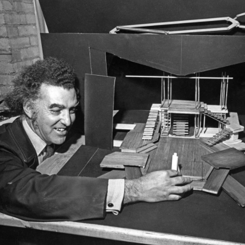 A black and white photo of Murray Bernard Laufer, interacting with a diorama of a theatre stage