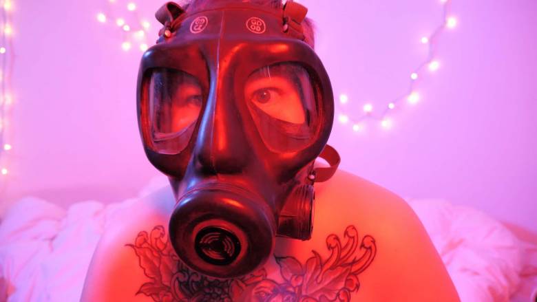 Portrait of a person wearing a gas mask with ambient pink lighting