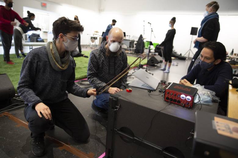 A photo of 3 people testing a musical instrument.