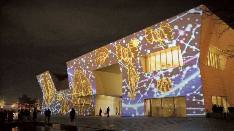 Photo of Aga Khan Museum with a work of art projected onto the building at night
