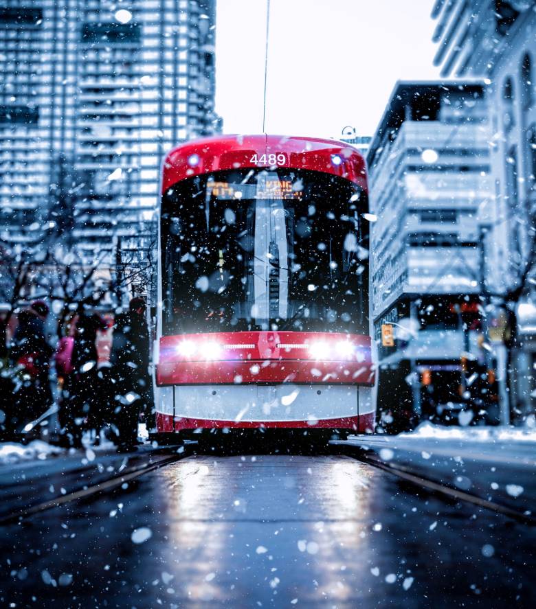 A photo of a Toronto streetcar on a busy street and snowy day. 