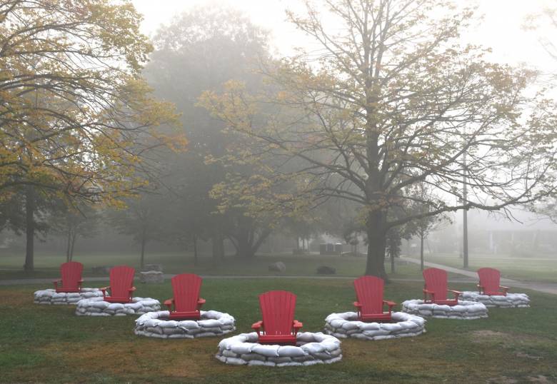 an outdoor art installation with red outdoor chairs in rings of rocks