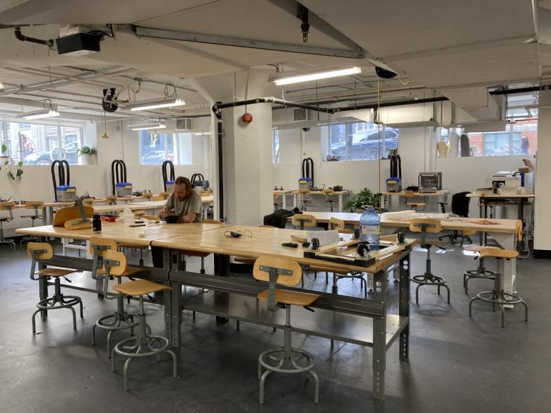 Equipment and tables set up in the Experimental Fabrication Studio and one man sitting at one of the tables. 