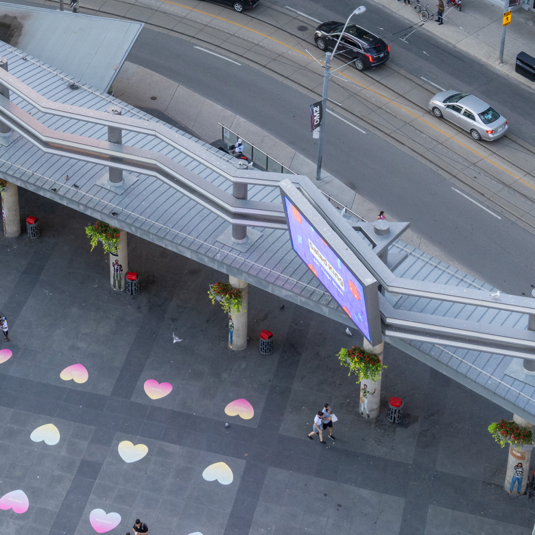 Birds eye view of a screen located in Yonge and Dundas Square with people walking around.