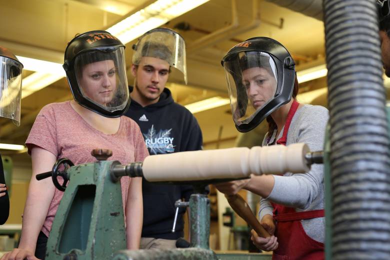 Three students working at a lathe
