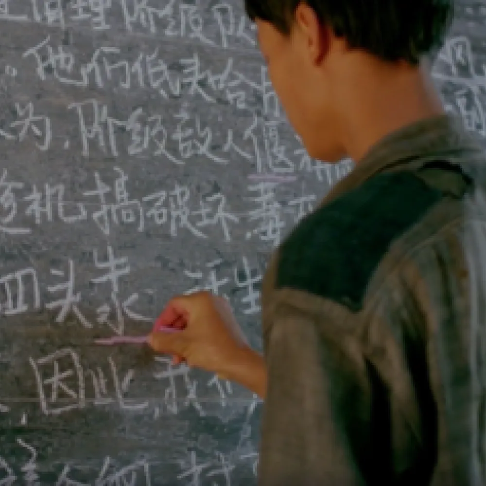 Person writing Chinese on blackboard