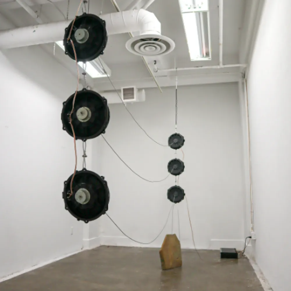 Fans hanging from the ceiling in a gallery space