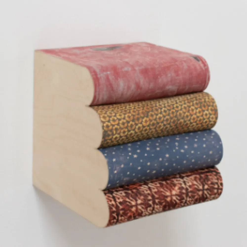 Sculpture of books sitting against a wall